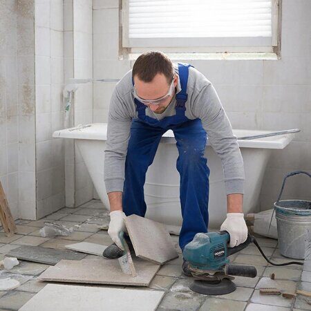 изображение человека который режит керамогранит болгаркой в ванной комнате