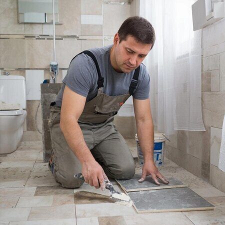 изображение человека который клеит керамогранит в ванной комнате